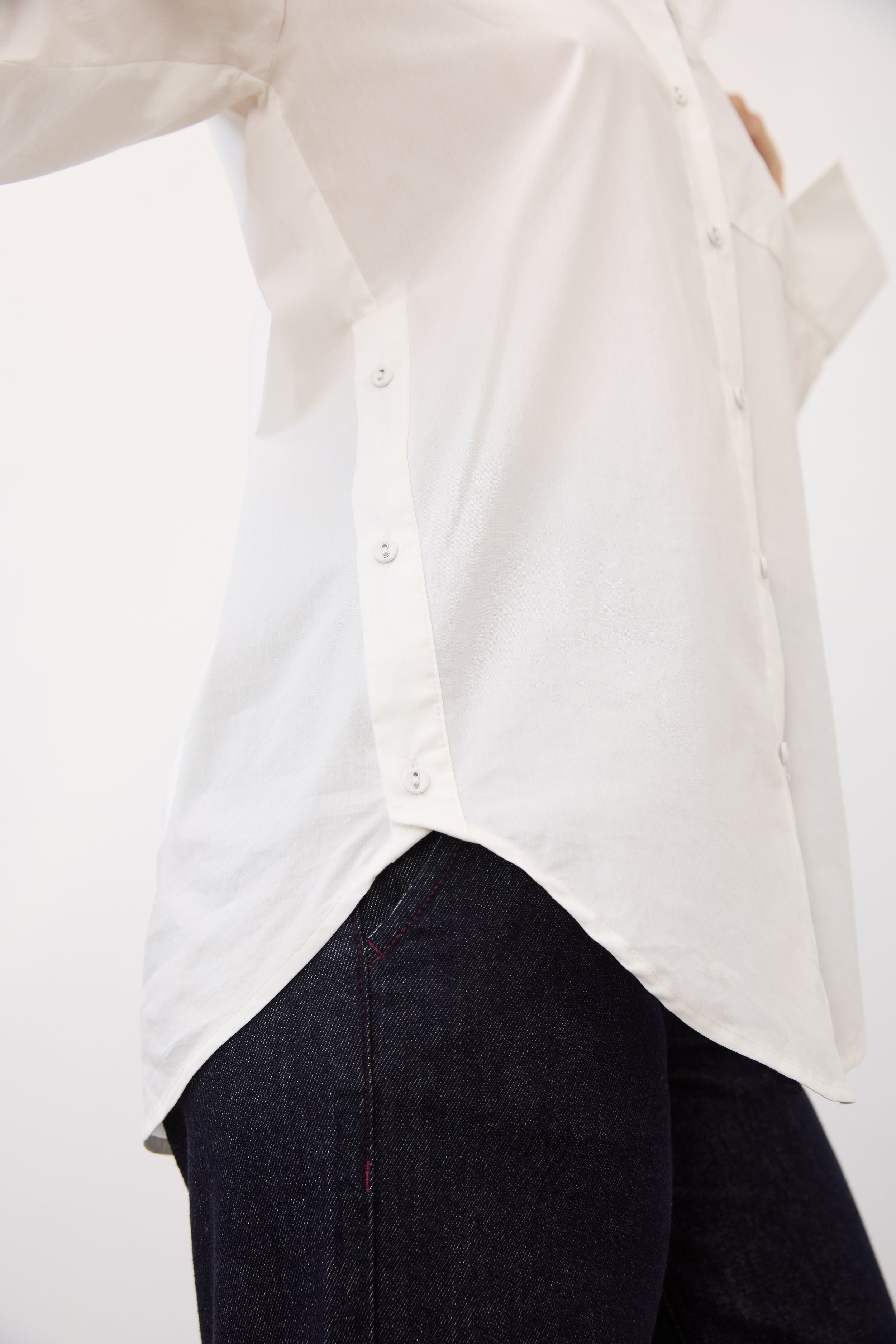 Side detail of white shirt showing curved hem and buttoned sides by French Dressing Jeans (FDJ)